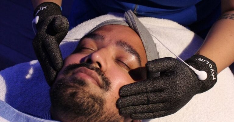 Esthetician using microcurrent gloves on a client's cheek and jawline at Nios Skin Lab
